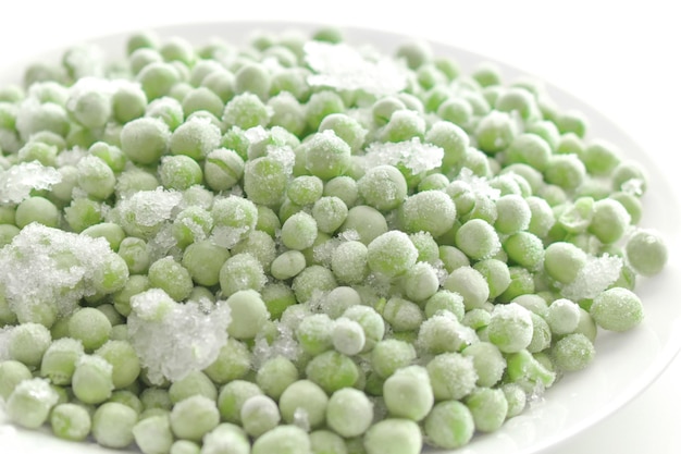 Photo frozen green peas on a white plate