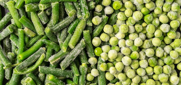 Frozen green string beans and peas on black background, flat lay.