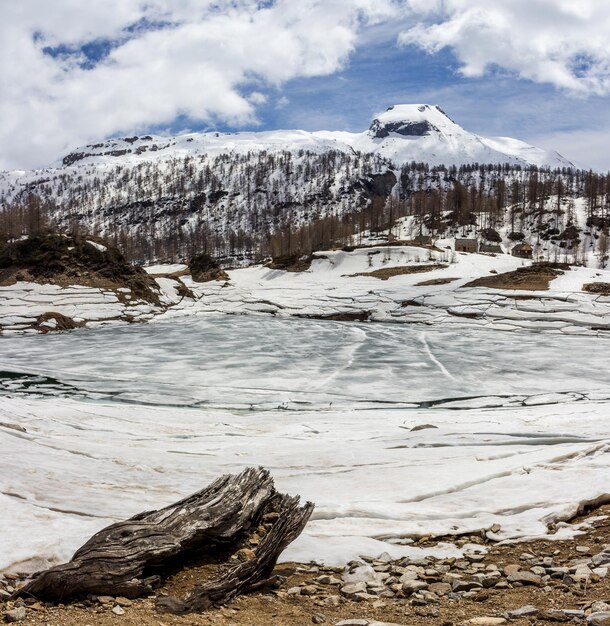 Photo frozen lake by snowcapped mountains against cloudy sky