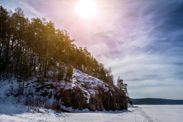 Frozen lake covered with snow with rocky shores in winter