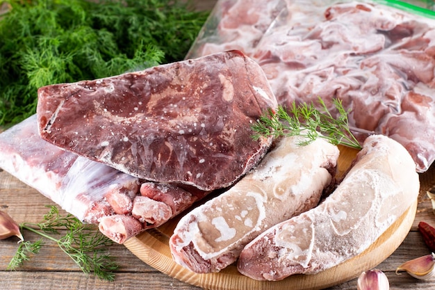 Frozen meat. frozen offal, liver, heart, stomachs in a plastic\
bag on a wooden table. frozen products. frozen food