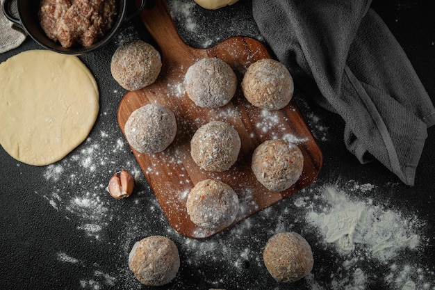 Foto polpette congelate con spezie su un tagliere su sfondo scuro con farina ingredienti crudi per cucinare il cibo