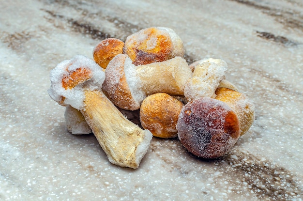 Frozen mushrooms on a wooden background. The whole boletus is frozen in the freezer.