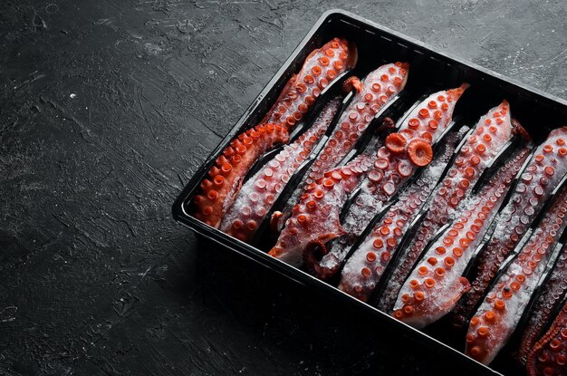 Frozen octopus tentacles in a plastic box Top view Flat lay