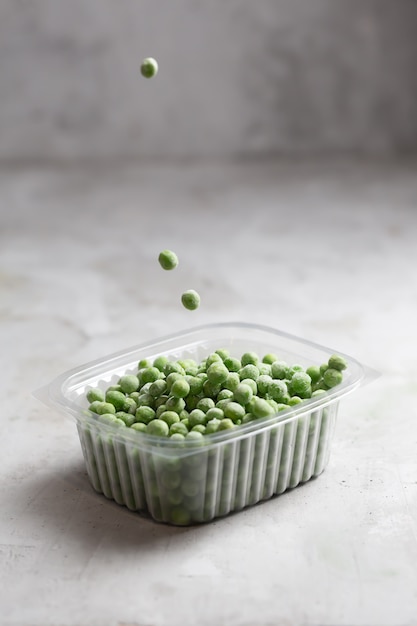 Frozen pea in the storage boxe on the gray concrete space