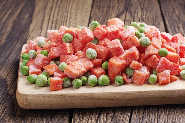 Frozen peas and carrots on a cutting board