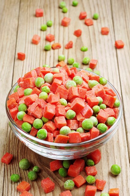 Frozen peas and carrots on a wooden table