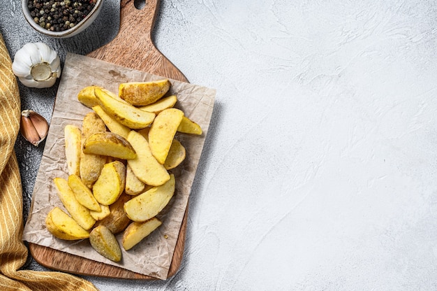 Frozen potato wedges on a cutting board. Recipe for French Fries. White background. Top view. Copy space.