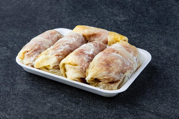 Frozen preparing tasty stuffed cabbage rolls on table in kitchen