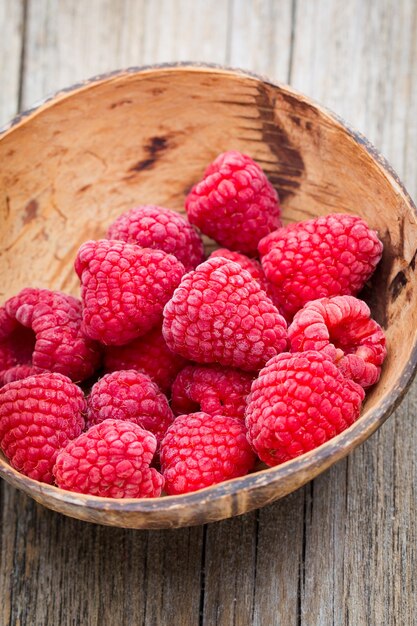 Frozen raspberries on wooden background.