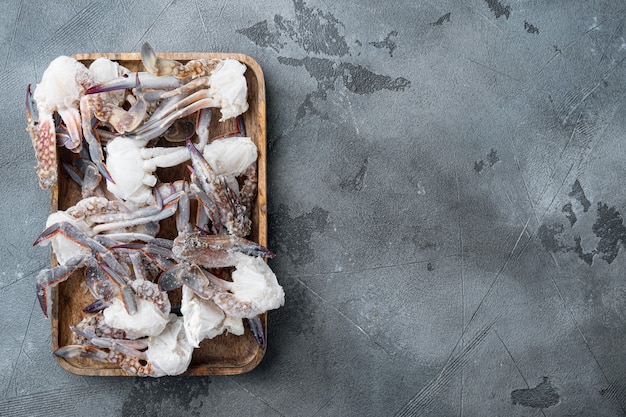 Frozen raw blue swimming crab meat set, on wooden tray, on gray background, top view flat lay , with copyspace  and space for text