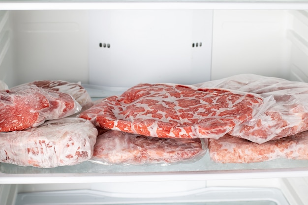 Frozen raw meat wrapped plastic in the freezer. frozen\
food