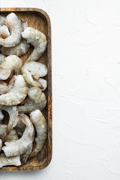 Frozen raw uncooked tiger prawns shrimps on wooden tray