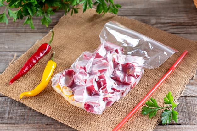 Frozen red peppers. Frozen hot pepper on a wooden board on the table. Frozen food. Frozen vegetables.