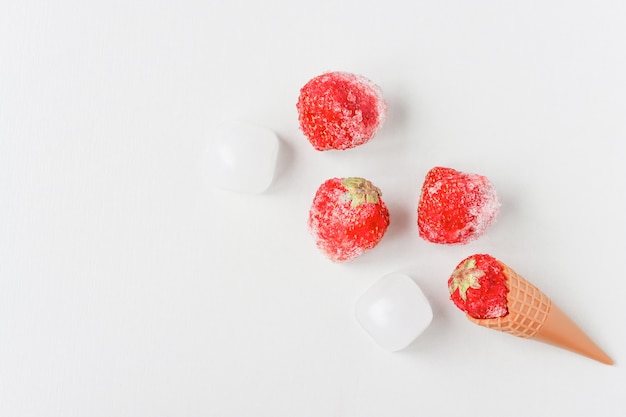 Frozen ripe strawberries and ice on a light wooden table the concept of ice cream and freezing