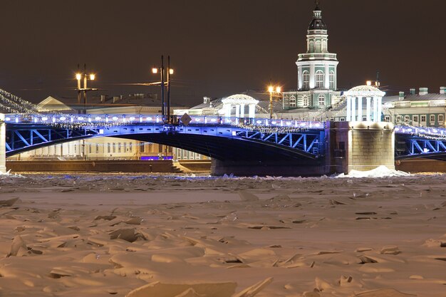 Frozen river, beautiful glowing bridge with Christmas decorations.