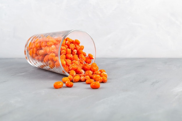 Frozen sea buckthorn berries spilled out of glass on the table Selective focus copy space