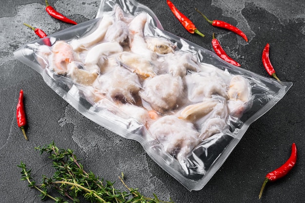 Frozen seafood set, squid rings, shrimp and octopus vacuum Packed set, on black dark stone table background
