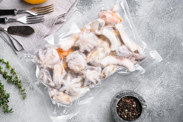 Frozen seafood set, squid rings, shrimp and octopus vacuum Packed set, on gray stone table background, top view flat lay