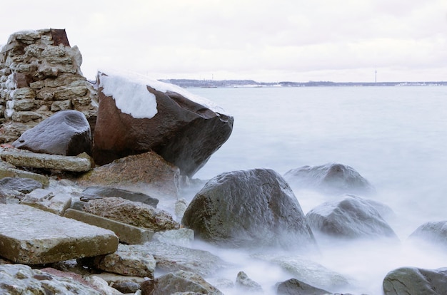 Замерзшая морская вода на камнях во время шторма