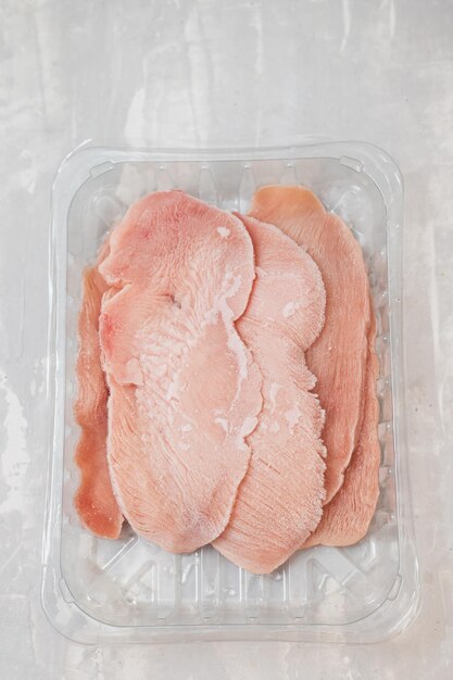 プラスチックの箱に入った冷凍スライスした肉の七面鳥