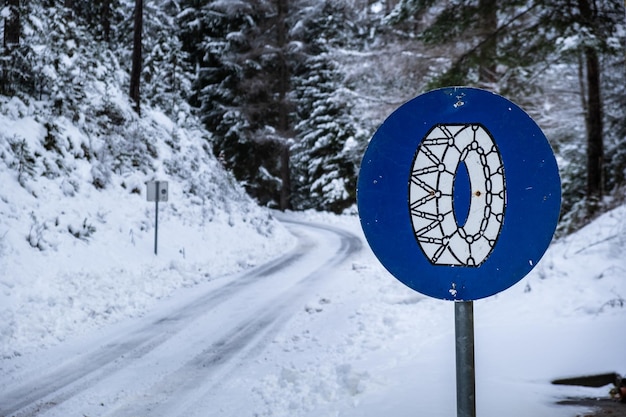 Frozen slippery road covered with snow through alpine forest