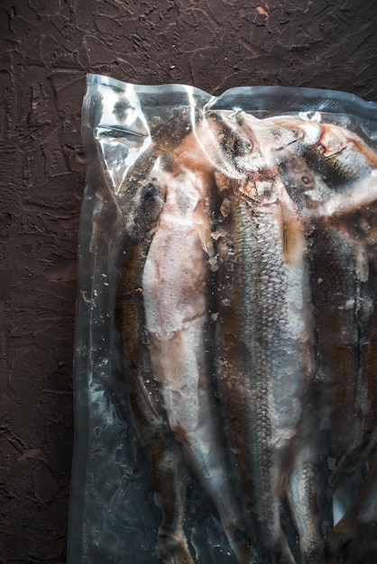 Frozen smelt in a vacuum package on a beige background closeup