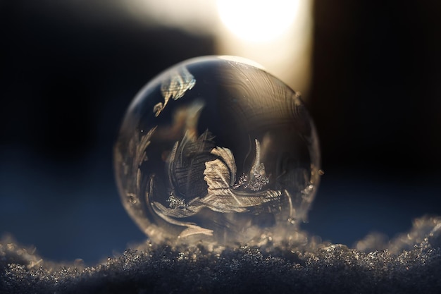 Frozen soap bubble with a beautiful pattern on the snow closeup on a blurry background