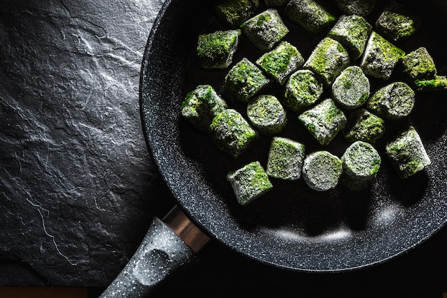 Frozen spinach in briquettes in a frying pan