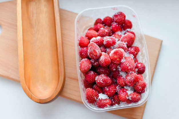 Frozen strawberries in plastic. Frozen strawberries in a plastic container in the freezer. Frozen berries