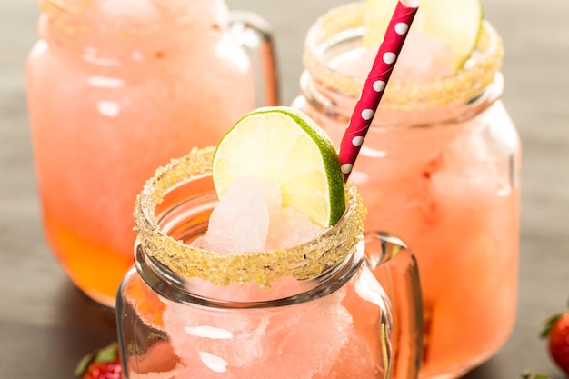 Frozen strawberry margarita cocktail in drinking mason jar.