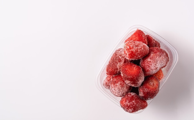 Frozen strawberry in plastic box isolated on white background,flat lay.