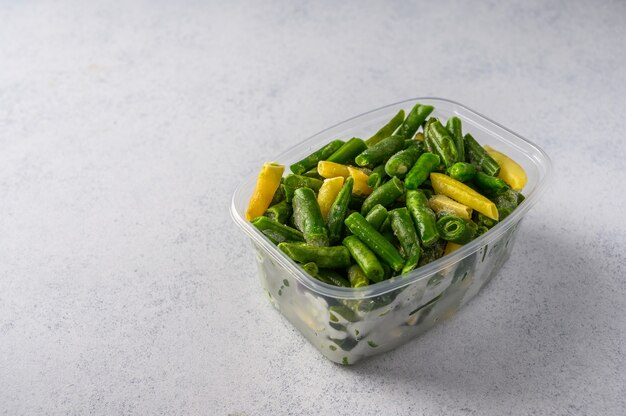 Frozen vegetables green pods beans in plastic tray on an gray surface selective focus concept