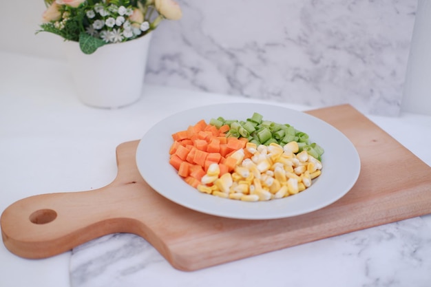 Frozen vegetables on a white plate on a white marble table