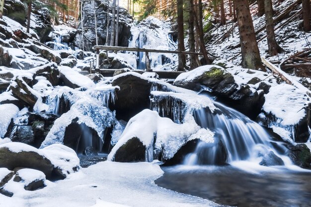 Frozen waterfalls with a wooden railing in the forest during hiking