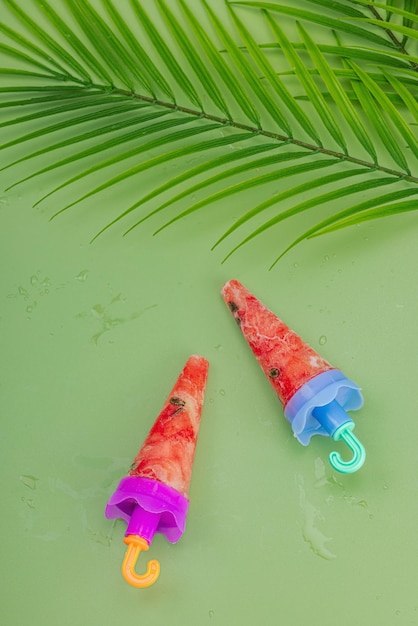 Frozen watermelon popsicles on trendy Savannah green background Refreshing summer dessert flat lay top view