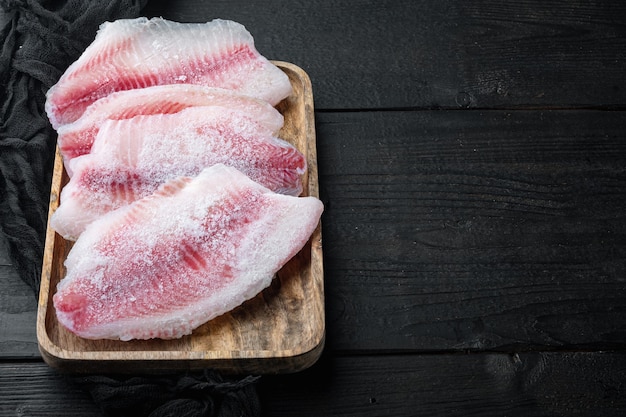 Frozen, white fish fillet, on black wooden table