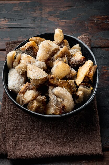 Frozen wild mushrooms set, in bowl, on old dark wooden table