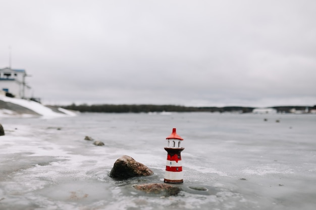 Mare invernale ghiacciato con faro decorativo