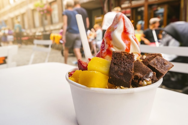 frozen yoghurt with brownie and fruits toppings on a table