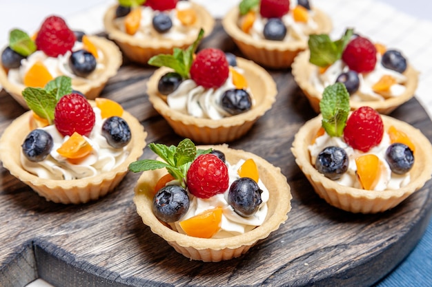 사진 나무 쟁반에 모듬 과일과 베리 tartlets 디저트