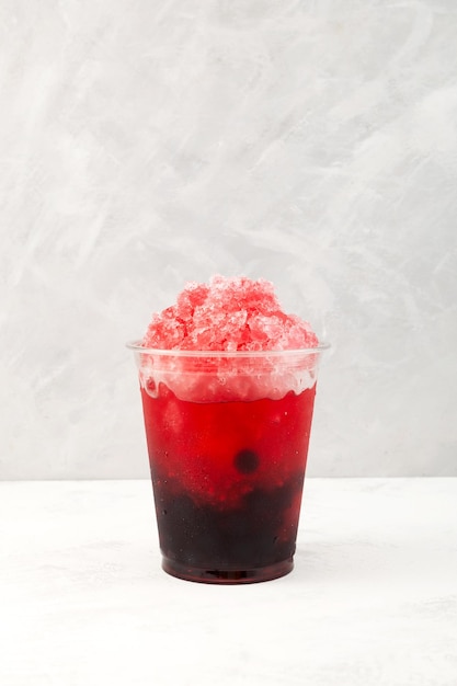 Fruit berries iced cocktail in disposable plastic cup Slushie drink Fruit shaved ice with juice