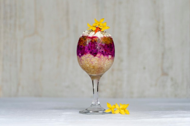 Fruit breakfast in a glass of oatmeal red dragon fruit passion fruit mango and honey in white wooden background close up The concept of healthy eating