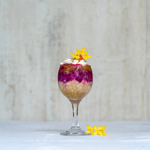 Fruit breakfast in a glass of oatmeal red dragon fruit passion fruit mango and honey in white wooden background closeup The concept of healthy eating