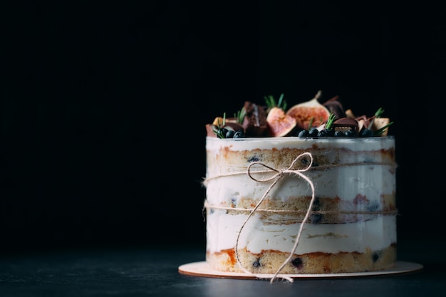 Fruit cake decorated with figs, cookies and blueberries.