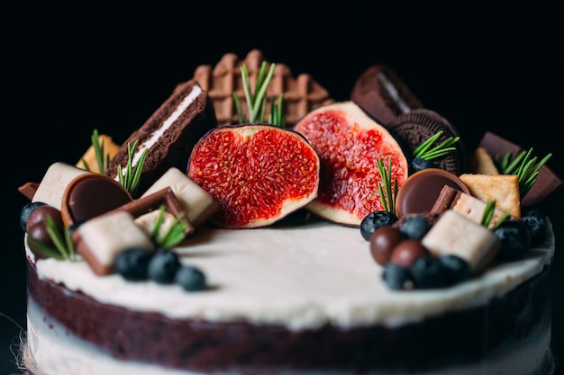 Fruit cake decorated with figs, cookies and blueberries.