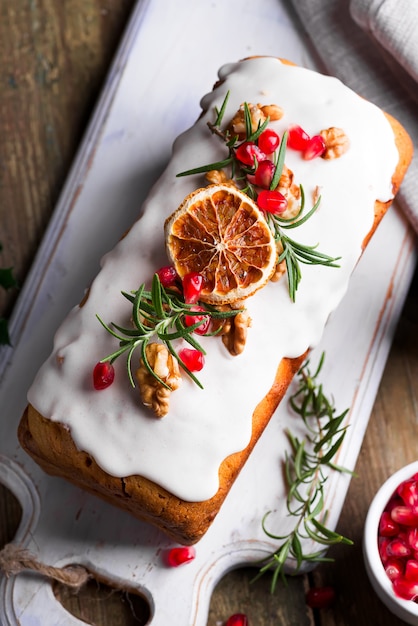 Фруктовый пирог посыпанный глазурью, орехами, зернами граната и сухой апельсин крупным планом. Рождественские и зимние каникулы домашнего торта