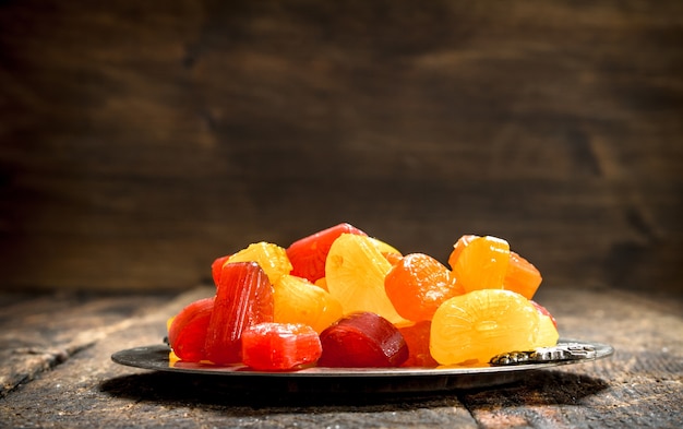 Fruit candies on a steel tray. On a wooden background.