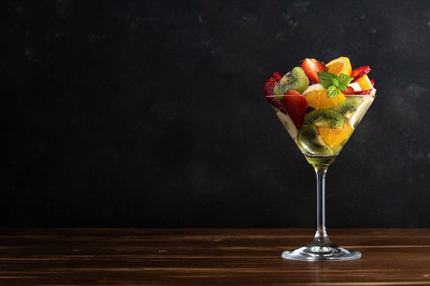 Fruit cocktail in martini glass on wooden table.