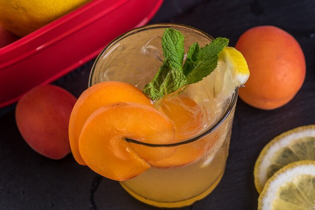 Fruit cocktail with fresh fruits and ice. In glasses on rustic black wooden background